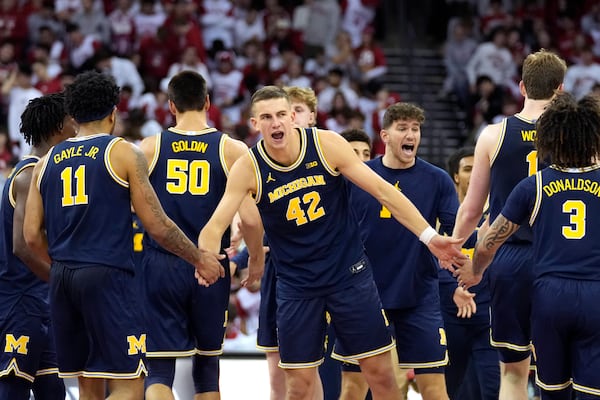 Michigan forward Will Tschetter (42) high-fives teammates Michigan guard Roddy Gayle Jr. (11) and Michigan guard Tre Donaldson (3) as the Wolverines take the lead going into a timeout during the second half of an NCAA college basketball game agains Wisconsin Tuesday, Dec. 3, 2024, in Madison, Wis. Michigan won 67-64. (AP Photo/Kayla Wolf)