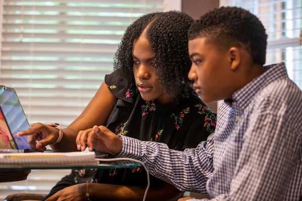 Cassidy Valbrun, left, homeschool’s her nephew Malachi Battle at the kitchen table at their residence in Grayson on May 18, 2021. Cassidy, a rising senior at Kennesaw State University, has been teaching Malachi ever since February when he was suspended from Couch Middle School for an alleged ‘Zoom Bombing’ during a virtual class. (Alyssa Pointer / Alyssa.Pointer@ajc.com)