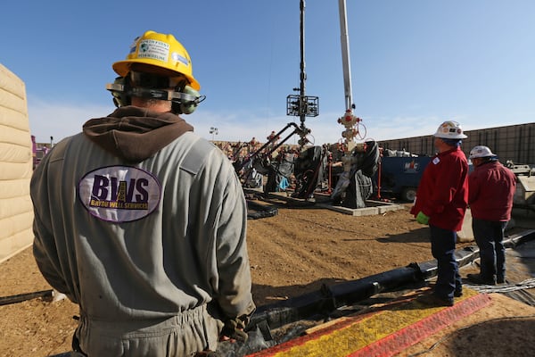 In this March 25, 2014 photo, workers keep an eye on well heads during a fracking operation, near Mead, Colo.  (AP Photo/Brennan Linsley)