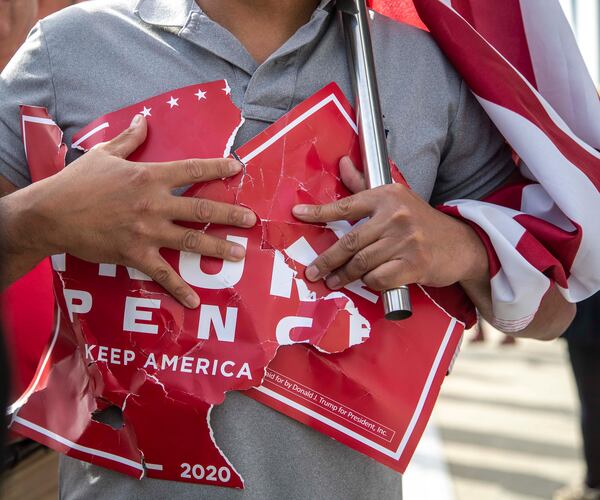 11/05/2020 —  Atlanta, Georgia — A President Donald Trump supporter holds onto a sign that was ripped during a rally outside of State Farm Arena in downtown Atlanta, Thursday, November 5, 2020. Inside State Farm Arena, workers were busy finishing up the process of counting ballots from Fulton County voters. (Alyssa Pointer / Alyssa.Pointer@ajc.com)