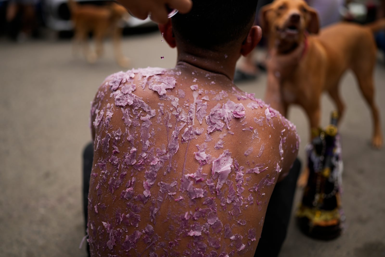 A woman drips candle wax on Valentin Solis as part of his penance, as pilgrims make their way, some crawling, to the San Felipe Church in Portobelo, Panama, Monday, Oct. 21, 2024, during a festival celebrating the iconic Black Christ statue that was found on the shore in 1658. (AP Photo/Matias Delacroix)