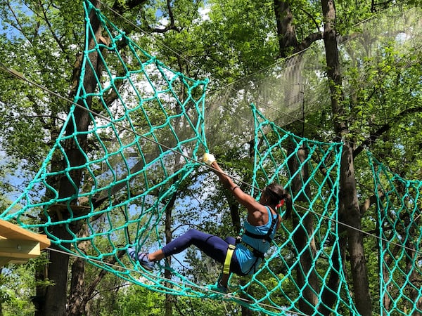 Participant tests her strength and fear of heights on this vertical cargo net.