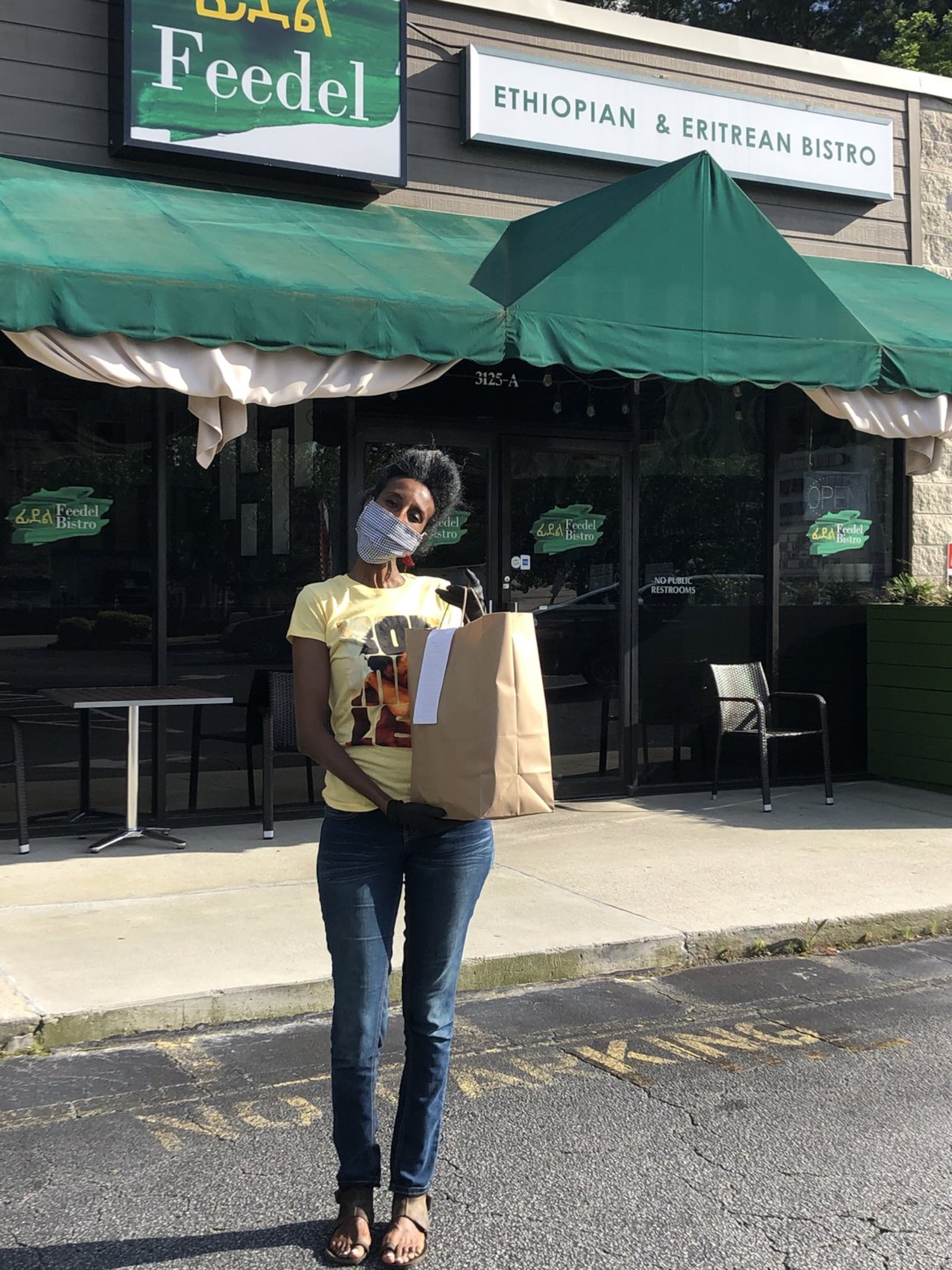 Feedel Bistro co-owner Tamar Telahun brings a takeout order to the parking lot of the Ethiopian and Eritrean restaurant on Briarcliff Road. CONTRIBUTED BY WENDELL BROCK