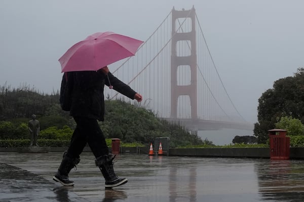 A pedestrian carrying an umbrella walks in front of the Golden Gate Bridge in San Francisco, Wednesday, Nov. 20, 2024. (AP Photo/Jeff Chiu)