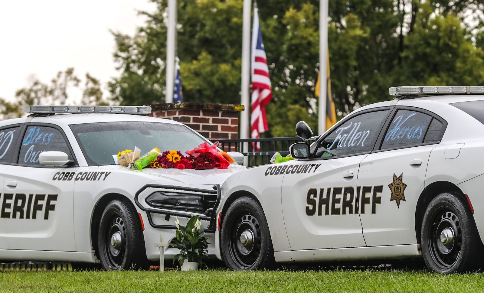 A memorial is growing outside the Cobb County Sheriff's Office, where mourners are leaving flowers on the patrol cars of slain deputies Jonathan Randall Koleski and Marshall Samual Ervin Jr.