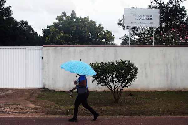 A woman walks near a sign for the Brazil Potash Corp. in Autazes, Amazonas state, Brazil, Wednesday, Feb. 19, 2025. (AP Photo/Edmar Barros)