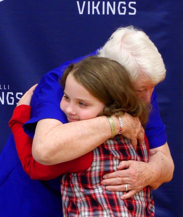 Sister Pat Thompson gets a hug from Emma Purdy, a third-grader at St. Anne-Pacelli Catholic School in Columbus, Georgia, at a Dec. 9, 2024, ceremony honoring Thompson and Sister Margaret Downing. (Photo Courtesy of Mike Haskey)