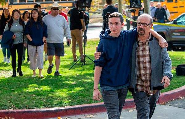 Student Patrick Karamian, 17, embraces his father Ara Karamian as they leave the reunification area in Central Park after being evacuated from Saugus High School.