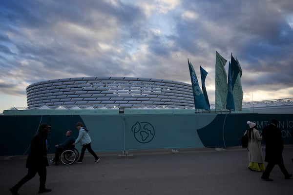 People walk outside the Baku Olympic Stadium, the venue for the COP29 U.N. Climate Summit, Wednesday, Nov. 13, 2024, in Baku, Azerbaijan. (AP Photo/Peter Dejong)