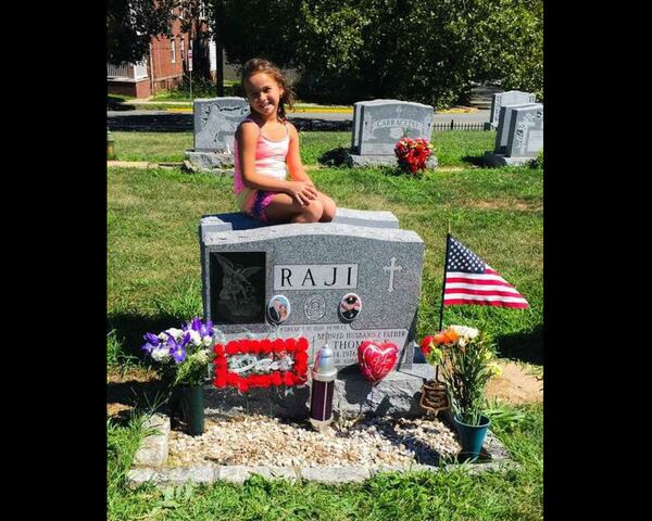 Mikayla Raji, 8, of Monroe, N.J., is pictured visiting the grave of her father, Perth Anboy police Officer Thomas Raji, who was killed in the line of duty seven months before her birth.