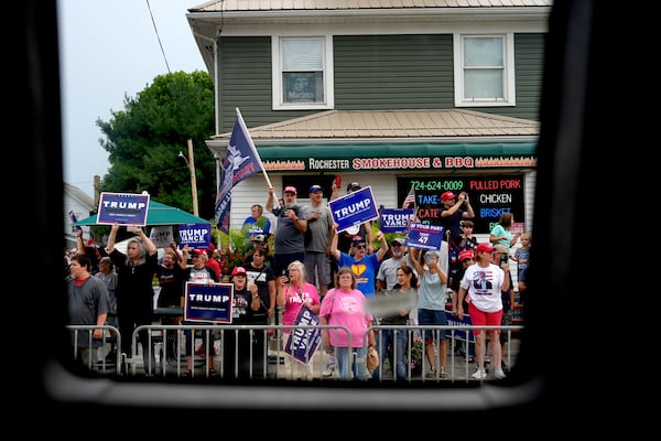 Supporters of Republican presidential candidate former President Donald Trump look on as a bus carrying Democratic presidential nominee Vice President Kamala Harris passes by following a campaign event, Sunday, Aug. 18, 2024, in Rochester, Pa. (AP Photo/Julia Demaree Nikhinson)