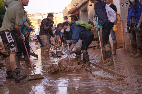 People sweep away mud during the clean up operation after flooding in Massanassa on the outskirts of Valencia, Spain, Wednesday, Nov. 6, 2024. (AP Photo/Alberto Saiz)