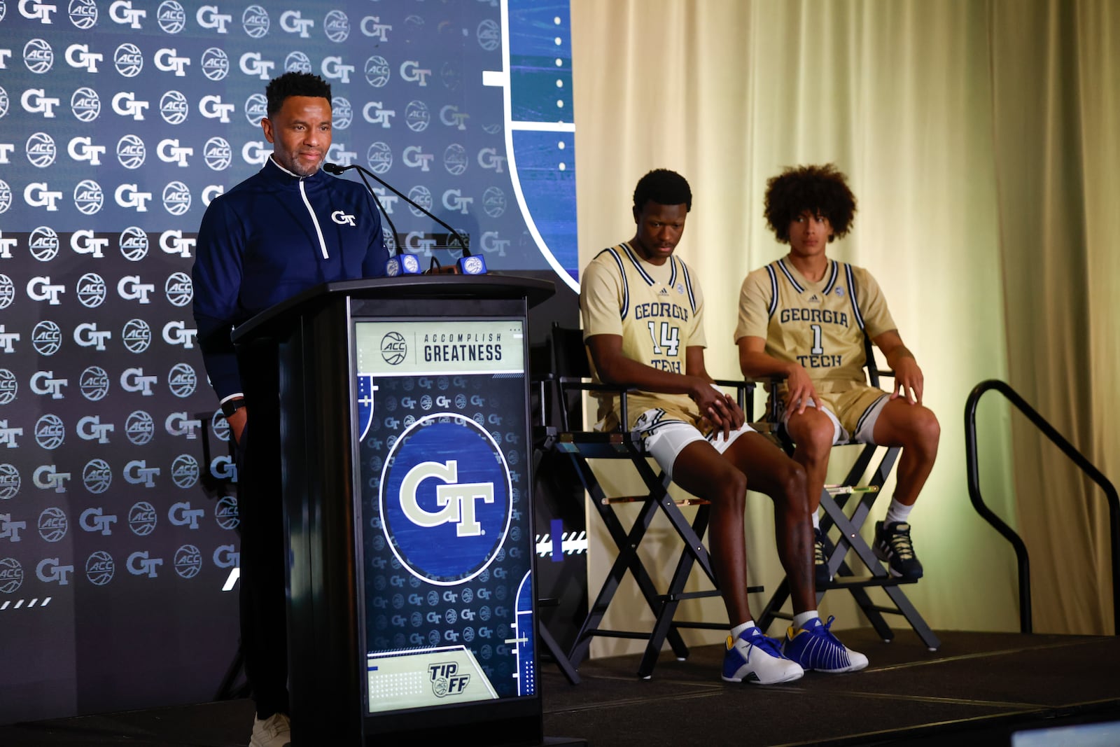 Georgia Tech coach Damon Stoudamire speaks to the media at the 2024 ACC Tipoff in Charlotte, N.C., Wednesday, Oct. 9, 2024. To his left are Tech players Kowacie Reeves Jr. (14) and Naithan George. (Photo by Nell Redmond/ACC)