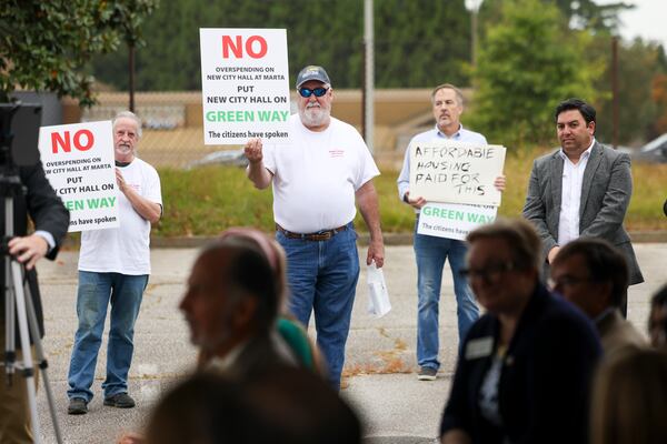 Longtime Brookhaven resident Ronnie Mayer, center, and others protest the spending on Brookhaven’s City Hall during the groundbreaking ceremony for Brookhaven’s $78 million City Hall at the Brookhaven MARTA Station parking lot, Wednesday, October 11, 2023, in Atlanta. (Jason Getz / Jason.Getz@ajc.com)