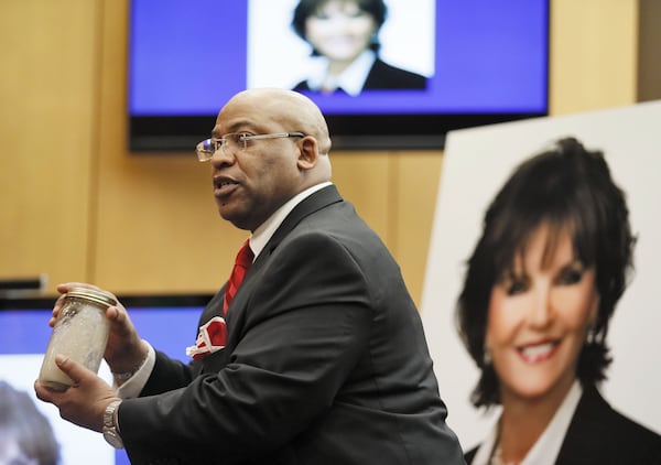 Chief Assistant District Attorney Clint Rucker, with a photo of Diane McIver behind him, holds a jar of sandy water, saying it will be crystal clear when he concludes, as he makes closing arguments for the prosecution during Tex McIver's trial. (Bob Andres)