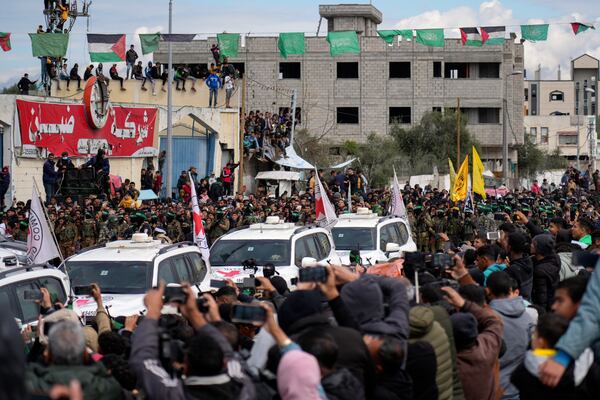 Palestinians gather as Hamas fighters escort Red Cross vehicles ahead of the handover of Israeli hostages in Nuseirat, central Gaza Strip, on Saturday, Feb. 22, 2025. (AP Photo/Abdel Kareem Hana)