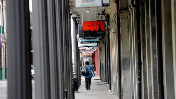 A man walks with some possessions alongside Jackson Square in the French Quarter of New Orleans, normally bustling with tourists, but now nearly deserted due to the new coronavirus pandemic, Friday, March 27, 2020. (AP Photo/Gerald Herbert)