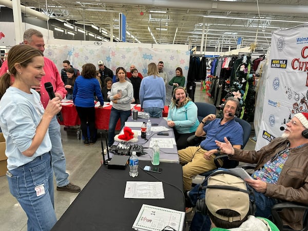 Clark Howard's wife Lane banters with him live on WSB radio Dec. 8, 2024 at the Roswell Walmart for Clark's Christmas Kids. Eric Von Haessler, a WSB afternoon host, is speaking on the right. RODNEY HO/rho@ajc.com