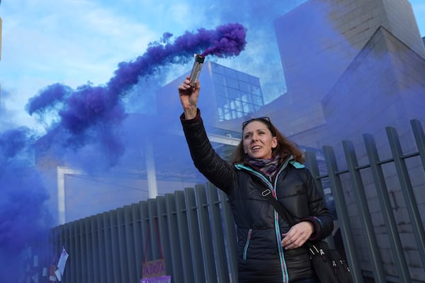 A woman fires a flare outside the Palace of Justice during a women's rights demonstration, Saturday, Dec. 14, 2024 in Avignon, southern France, where the trial of dozens of men accused of raping Gisèle Pelicot while she was drugged and rendered unconscious by her husband is taking place. (AP Photo/Aurelien Morissard)