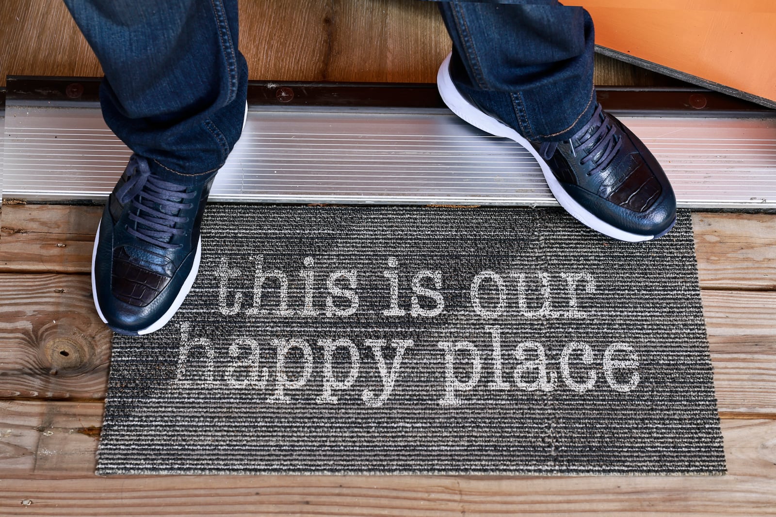 Rich Munroe, stands on a mat that says 
This is our happy place” on the patio of one of his rental properties on Tuesday, July 26, 2022. (Natrice Miller/natrice.miller@ajc.com)