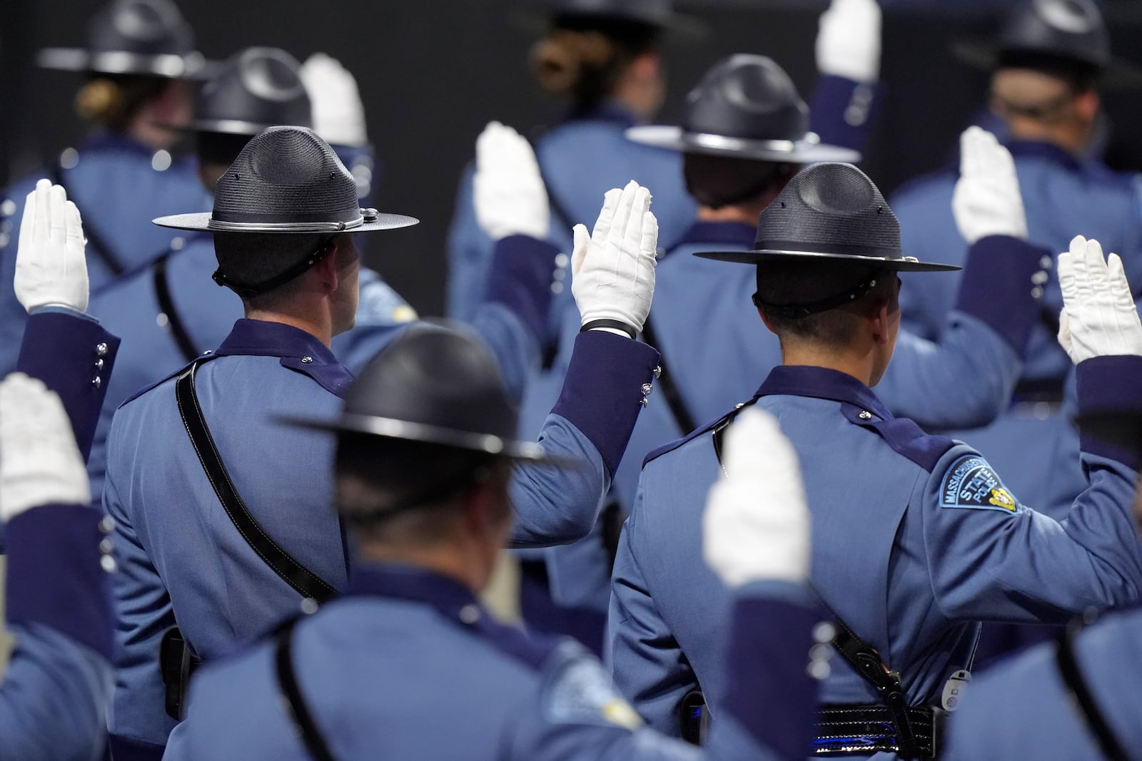 Members of the Massachusetts State Police 90th Recruit Training Group raise their hands as they are sworn in as State Police Troopers by Mass. Gov. Maura Healey, not shown, during ceremonies, Wednesday, Oct. 9, 2024, at the DCU Center, in Worcester, Mass. (AP Photo/Steven Senne)