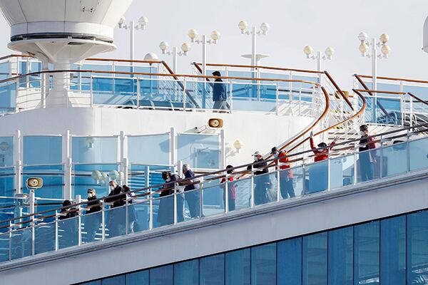 Passengers stand on the deck of the Diamond Princess cruise ship anchored at Yokohama Port in Yokohama, near Tokyo, on Wednesday.