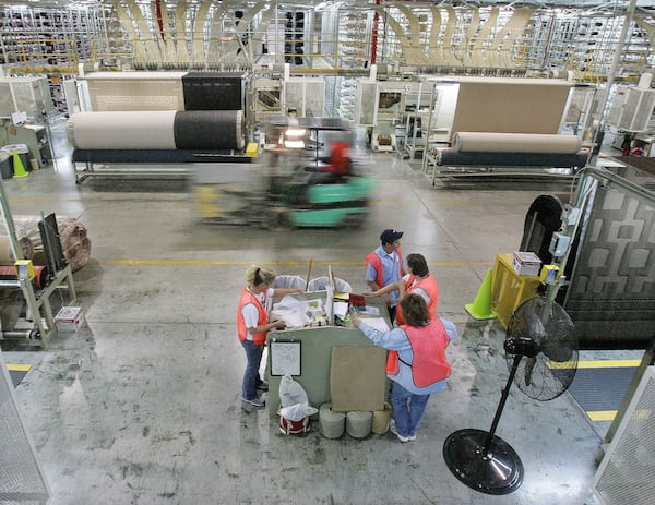 A forklift speeds by machines and workers on the production floor of a Mohawk Industries rug manufacturing plant in Calhoun, Ga., in 2006. Ric Feld/AP 2006.