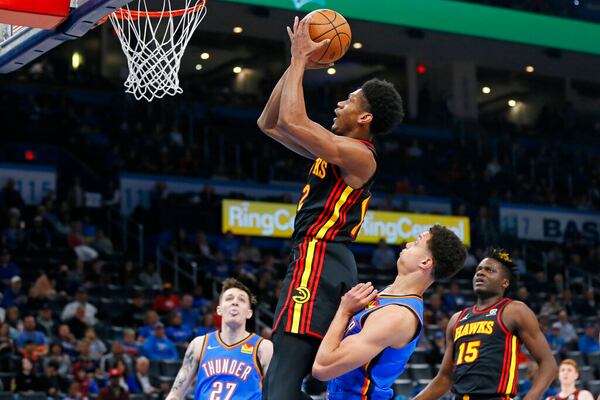 Atlanta Hawks forward De'Andre Hunter shoots between Oklahoma City Thunder guard Vit Krejci, left, and forward Isaiah Roby as Hawks center Clint Capela (15) watches during the first half of an NBA basketball game Wednesday, March 30, 2022, in Oklahoma City. (AP Photo/Nate Billings)