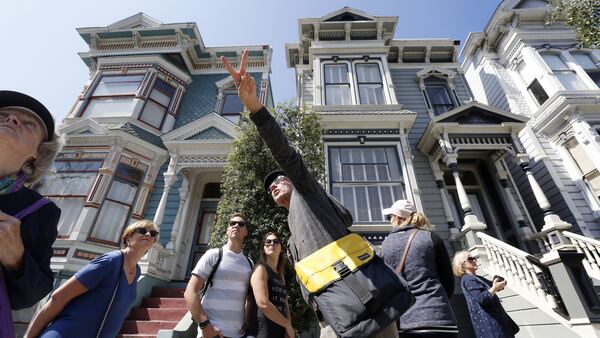 Participants of the Victorian Home Walk tour pause in front of a group of &quot;painted ladies&quot; victorian homes as host Jay Gifford, center, points out other types of building in the lower Pacific Heights neighborhood in San Francisco, Calif., on Friday, Sept. 15, 2017. Airbnb&apos;s new &quot;experiences&quot; feature allows people to use the platform to plan experiences as well as places to stay. (Laura A. Oda/Bay Area News Group/TNS)