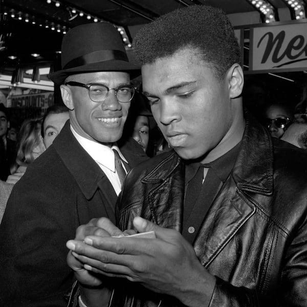 World heavyweight boxing champion Muhammad Ali  (right) stands with Malcolm X outside the Trans-Lux Newsreel Theater on Broadway at 49th Street in New York on March 1, 1964. They had just watched a screening of films on Ali's recent  title fight with Sonny Liston. Associated Press file 1964