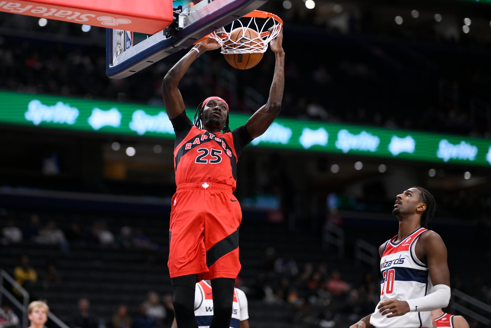 Toronto Raptors forward Chris Boucher (25) dunks past Washington Wizards forward Alex Sarr (20) during the first half of an NBA preseason basketball game, Friday, Oct. 11, 2024, in Washington. (AP Photo/Nick Wass)