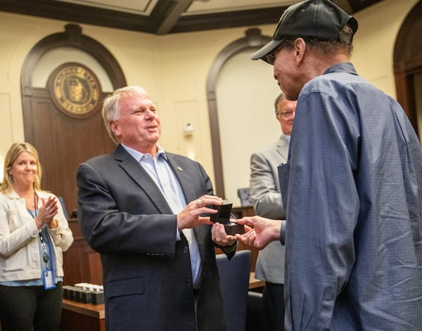 Alpharetta Mayor Jim Galvin, left, presents a State Championship ring to James Emerson, one of the Bailey-Johnson High School's basketball team of 1964-65 on Monday during the Alpharetta City Council meeting.  (Jenni Girtman for The Atlanta Journal-Constitution)