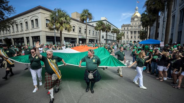 Members of The Guard Pipes and Drums from County Somerset, N.J. carry a large Irish flag while marching in the St. Patrick's Day parade on March 16, 2024, in Savannah, Ga.  (AJC Photo/Stephen B. Morton)