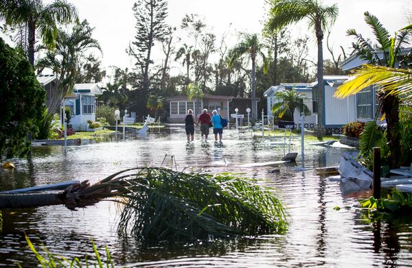 Larry Donnerstaf, center, is helped back to his home at Naples Estates trailer park in East Naples, Fla., on Sept. 11, 2017.