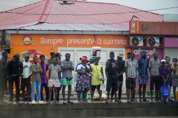 People watch President Joe Biden's motorcade drive through Luanda, Angola, Tuesday, Dec. 3, 2024. (AP Photo/Ben Curtis)