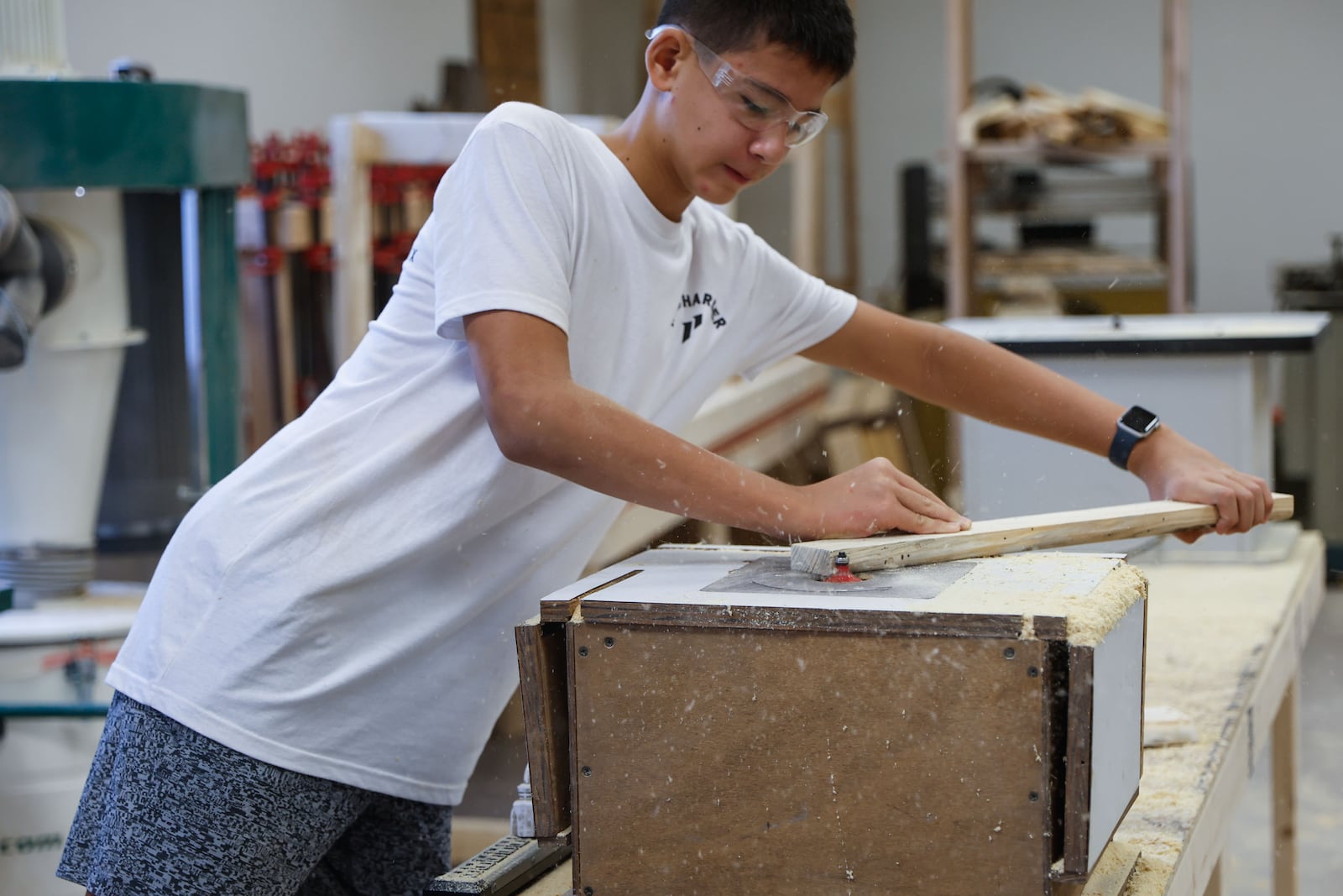 Nathan Chow, 13, an eighth grader at Elkins Pointe Middle School in Roswell, saws a piece of plywood during class. Chow says he really likes the class, but doesn't think he'll continue in high school. (Natrice Miller/AJC)