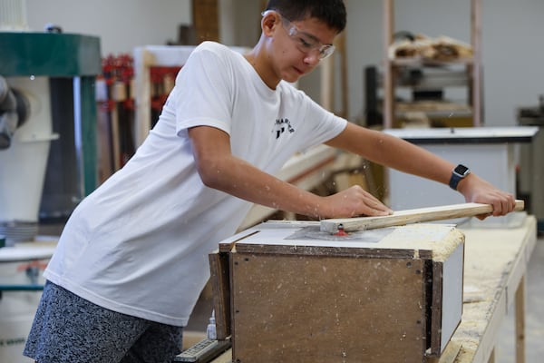 Nathan Chow, 13, an eighth grader at Elkins Pointe Middle School in Roswell, saws a piece of plywood during class. Chow says he really likes the class, but doesn't think he'll continue in high school. (Natrice Miller/AJC)