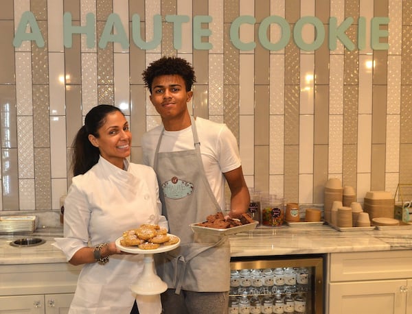 Shiana White (left), owner of A Haute Cookie, poses with son Cory Curtis, who works for A Haute Cookie, with White Chocolate Chunk Cookies with peppermint topping and brownies. CONTRIBUTED BY CHRIS HUNT PHOTOGRAPHY