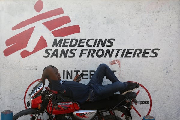 A taxi driver rests on his motorcycle against a facade of a Doctors Without Borders (MSF) clinic in Port-au-Prince, Haiti, Wednesday, Nov. 13, 2024. (AP Photo/Odelyn Joseph)