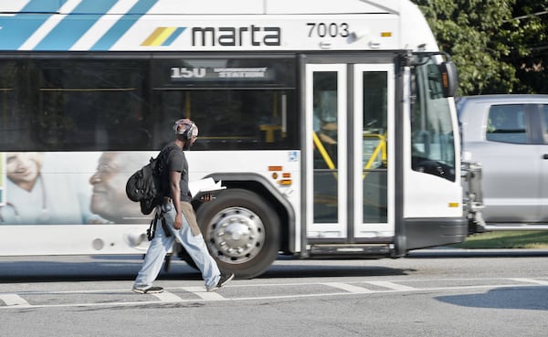 A pedestrian crosses in front of a MARTA bus in Dunwoody. (Bob Andres / robert.andres@ajc.com)