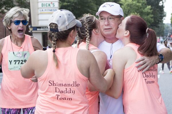 Adie Shimandle (left) set up some surprises for her husband, Rick. She signed him up for his first AJC Peachtree Road Race, and he was joined by his daughters, including Teanna Wilson (second from left), Kennsington Jones (center) and Alexandria Wilhite. JENNA EASON / JENNA.EASON@COXINC.COM