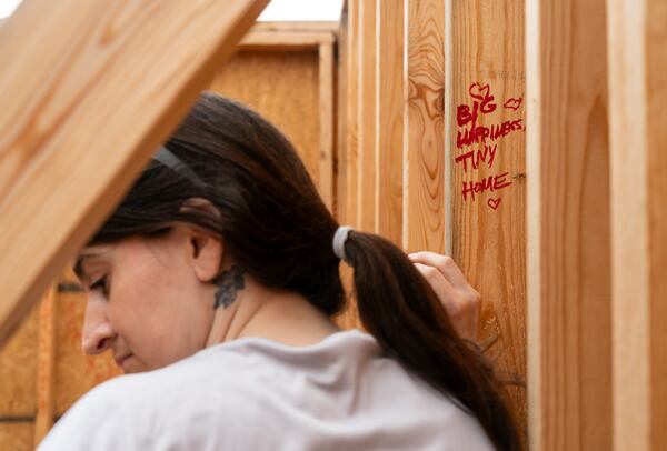 Amelia Laney, an inmate at the Athens-Clarke County Jail, writes a note in marker on a tiny home Laney and other inmates worked on in the jail yard in Athens, Ga., on Saturday, July 27, 2024. (Seeger Gray / AJC)