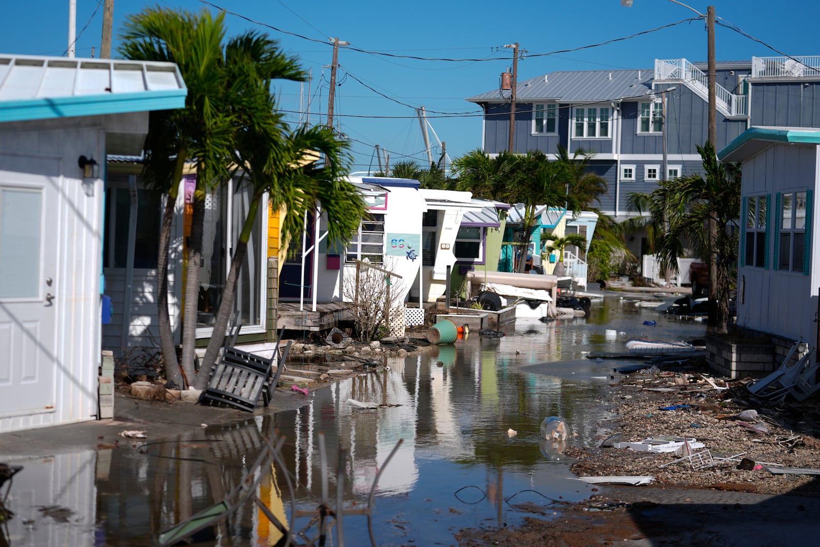 Water left by Hurricane Milton floods a road inside Pines Trailer Park, where debris was still piled outside homes from Hurricane Helene, in Bradenton Beach on Anna Maria Island, Fla., Thursday, Oct. 10, 2024. (AP Photo/Rebecca Blackwell)