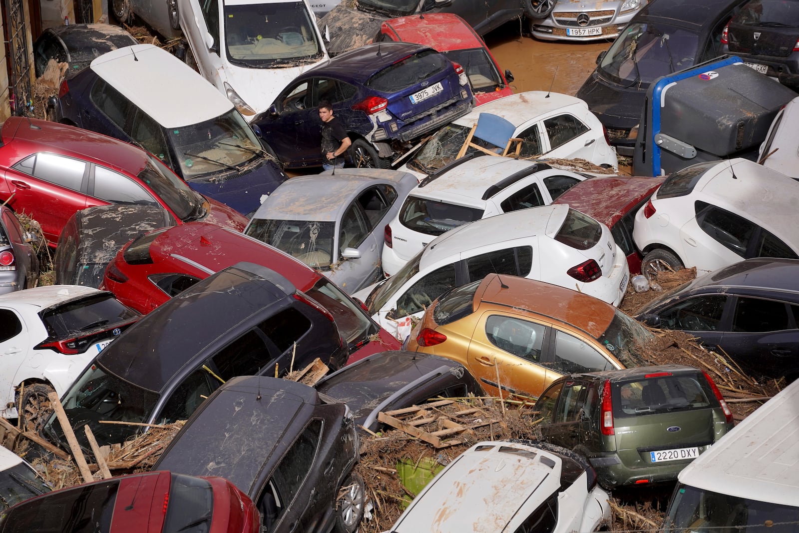 Residents look at cars piled up after being swept away by floods in Valencia, Spain, Wednesday, Oct. 30, 2024. (AP Photo/Alberto Saiz)