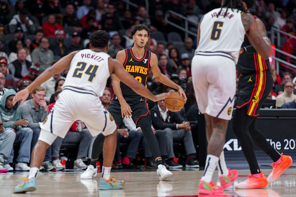 Atlanta Hawks forward Zaccharie Risacher, center, looks for an open teammate while guarded by Denver Nuggets guard Jalen Pickett (24) during the first half of an NBA basketball game on Sunday, Dec. 8, 2024, in Atlanta, at State Farm Arena. (Atlanta Journal-Constitution/Jason Allen)