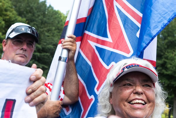 Sharon Anderson, from East Tennessee, right, and Mike Boatman, left, hold Trump flags in support of former President Trump as Rudy Giuliani speaks to the press after booking himself into the Fulton County Jail on Wednesday in Atlanta. (Michael Blackshire/Michael.blackshire@ajc.com)