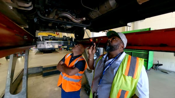 Cobb transportation workers examine the undercarriage of a paratransit vehicle