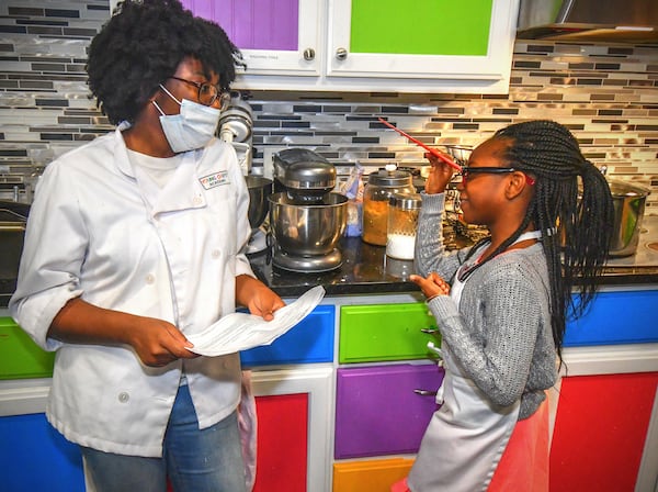 Young Chefs Academy instructor Deeyona Massay goes over instructions on how to make whipped cream with student Toni Tomori, 7, of Nigeria during a recent class. CONTRIBUTED BY CHRIS HUNT PHOTOGRAPHY