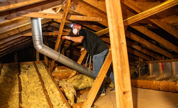 Ben Reeves gets started looking for ventilation fans to seal and route outside before adding insulation to the attic of this Roswell home, working to make the home more efficient on Wednesday, April 19, 2023. New federal tax credits for home energy improvements incentivize home owners to invest in an energy audit and update air leaks, add insulation and improve home efficiency to get federal tax credits, rebates and other financial benefits including with Georgia Power.  (Jenni Girtman for The Atlanta Journal-Constitution)