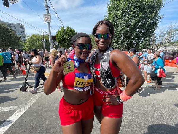 Marvellous Wells , right, and Kristin Johnson, left, show off their medals at the end of the AJC Peachtree Road Race.